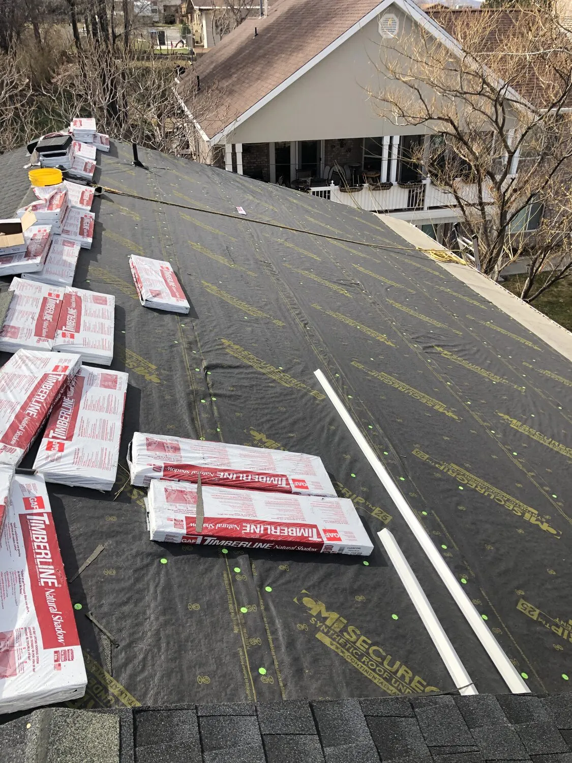Synthetic underlayment down with GAF Timberline shingle bundles staged across the roof