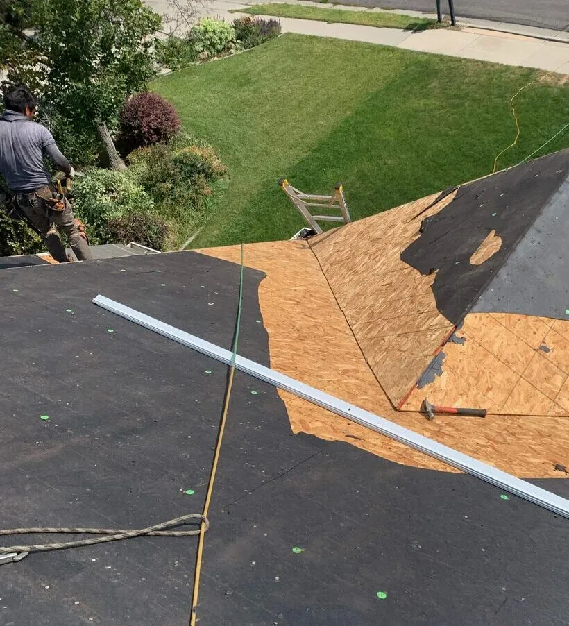 Crew member standing on the roof overlooking the work area during a tear-off
